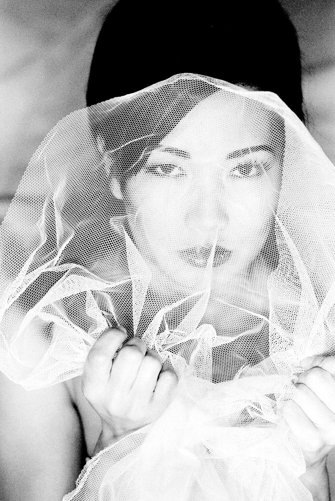 Portrait of woman clutching veiln front of her.